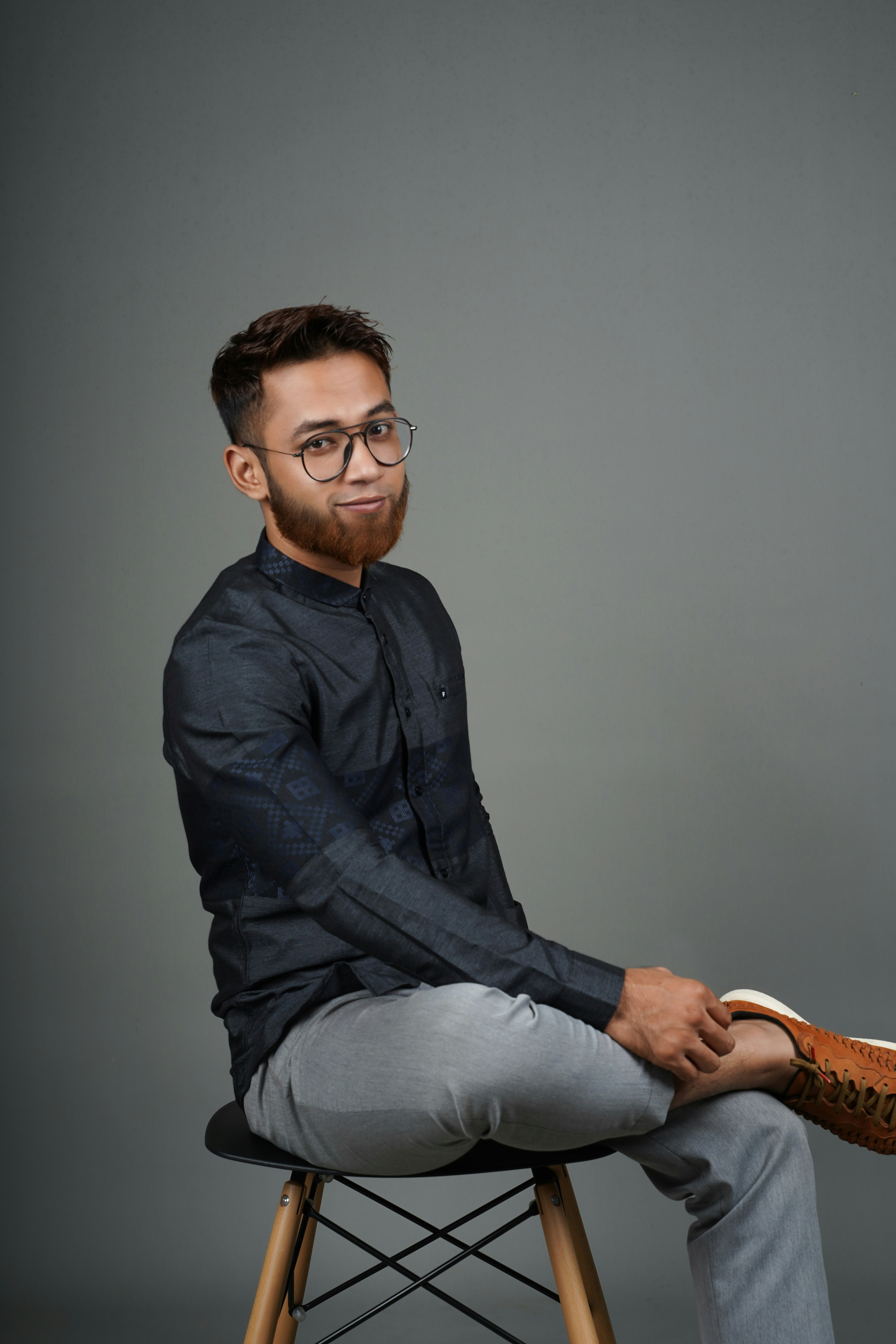 man in black dress shirt and blue denim jeans wearing black framed eyeglasses